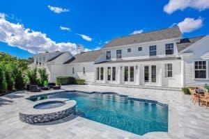 Modern white house with a large backyard swimming pool and spa.
